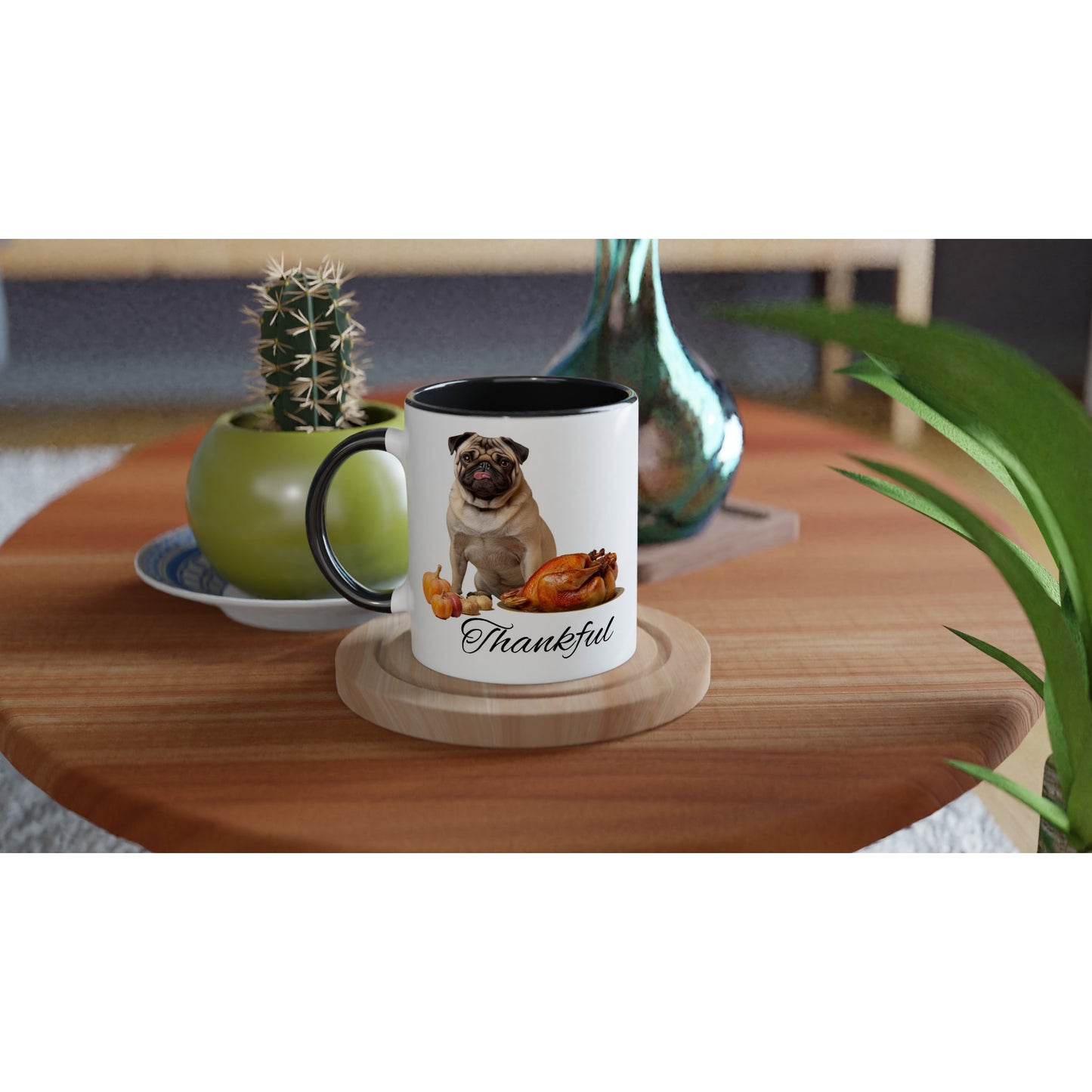 Round wooden end table with a potted cactus and vase and a mug on it. The mug is a white mug with black handle, rim, and inside with a picture of a pug sitting behind pumpkins and a roast turkey with the word "Thankful" under it.
