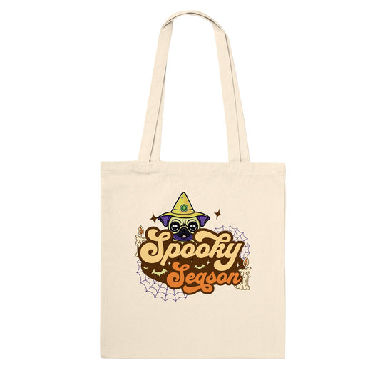 Natural beige colored tote bag with the image of a pug's head in a witch's hat and the words "Spooky Season" below it. The image also has cobwebs, bats, and candles in it.