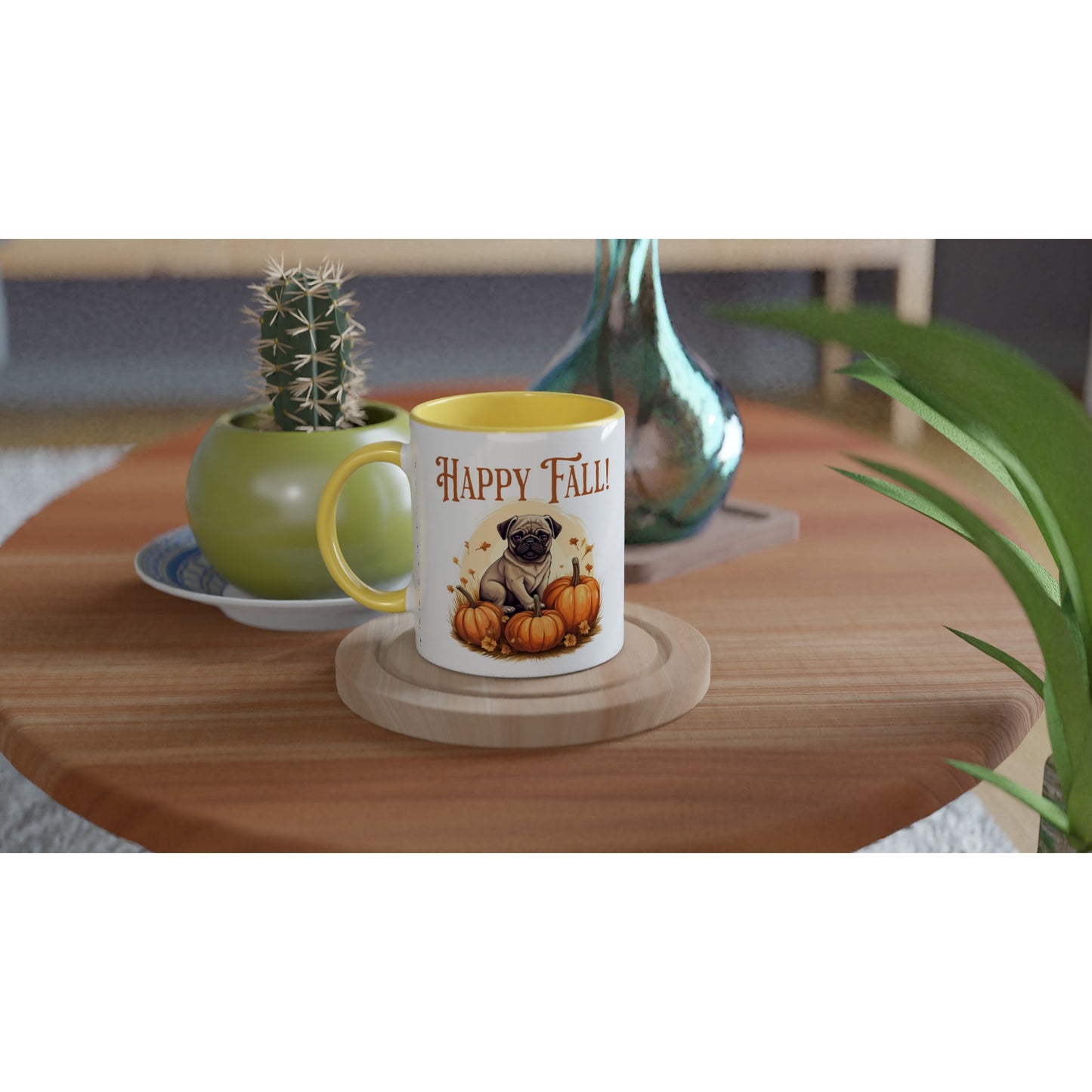 Round wooden end table with a potted cactus, glass vase, and white mug on it. The mug has a yellow handle, rim, and inside and a picture of a pug sitting in a pumpkin patch