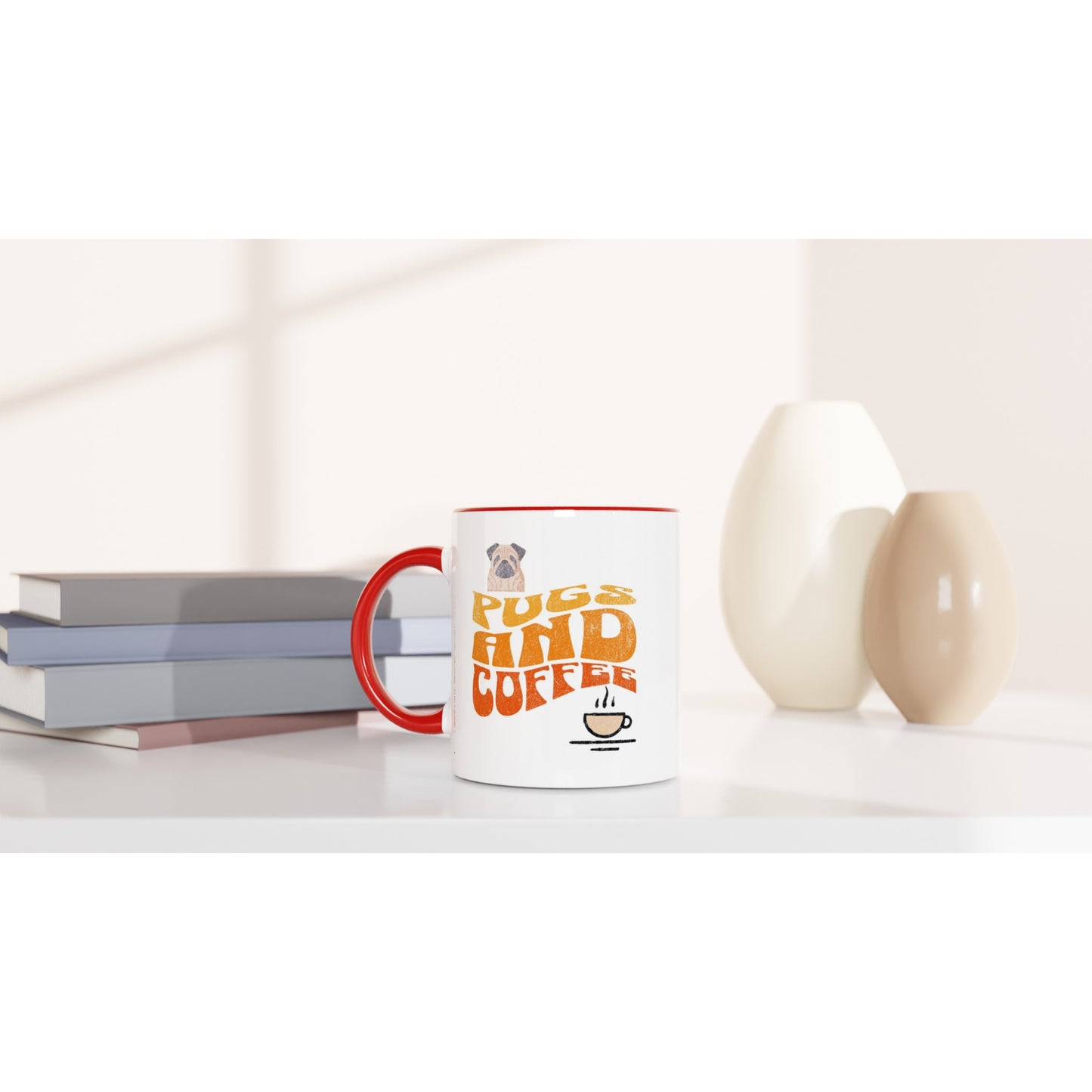 White coffee table with 4 stacked books and 2 oval vases and a mug on it. The mug is white with a red handle, rim, and inside with  the words "Pugs and Coffee" in yellow, orange, and red in a retro, faded, wavy style. There is a picture of a cartoon pug above the words on the left and a line-drawing of a steaming cup of coffee below the words on the right.