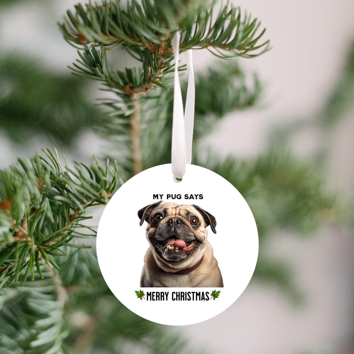 3 inch round flat white ornament hanging in a Christmas tree with a picture of the head and shoulders of a fawn-colored pug with the words "My pug says" above the pug and "Merry Christmas" below the pug. 